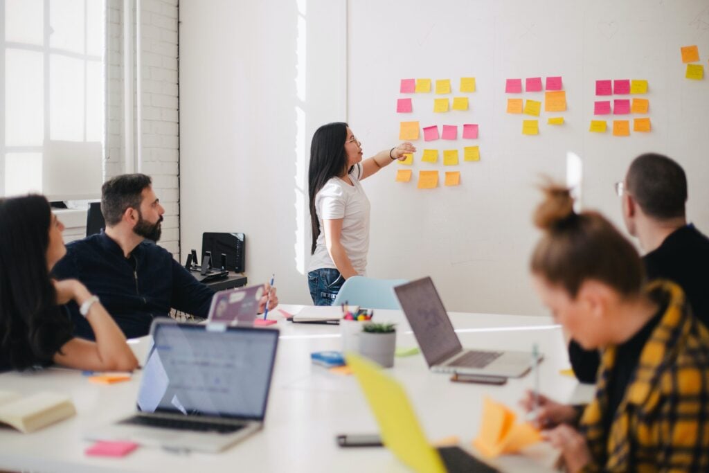 Woman gestures to sticky notes on white wall