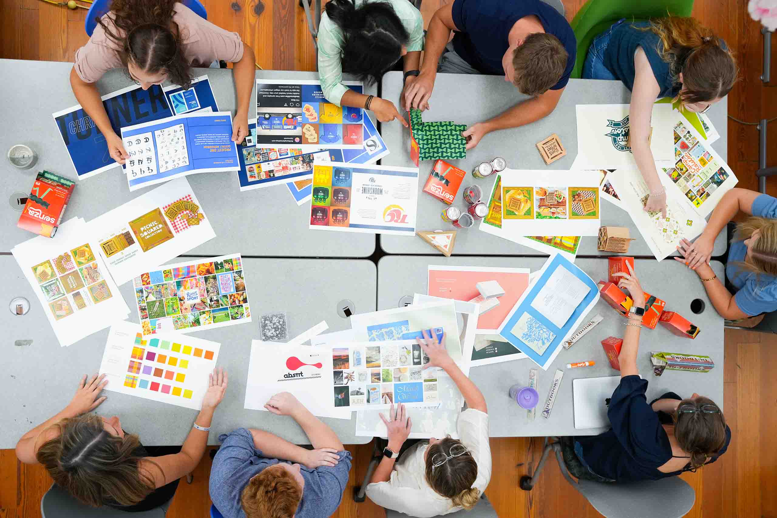 Overhead view of MASD students around table talking about projects.