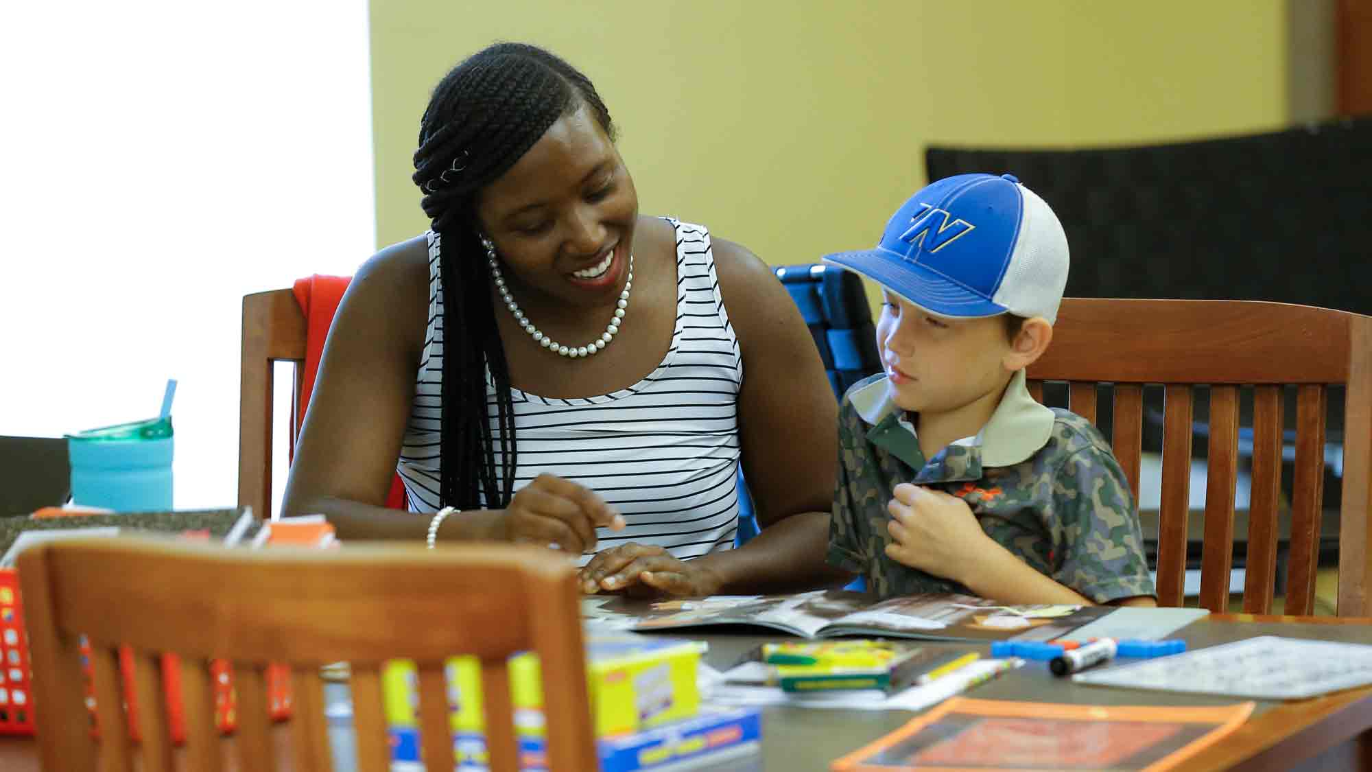 Woman and boy sitting at a table reading.