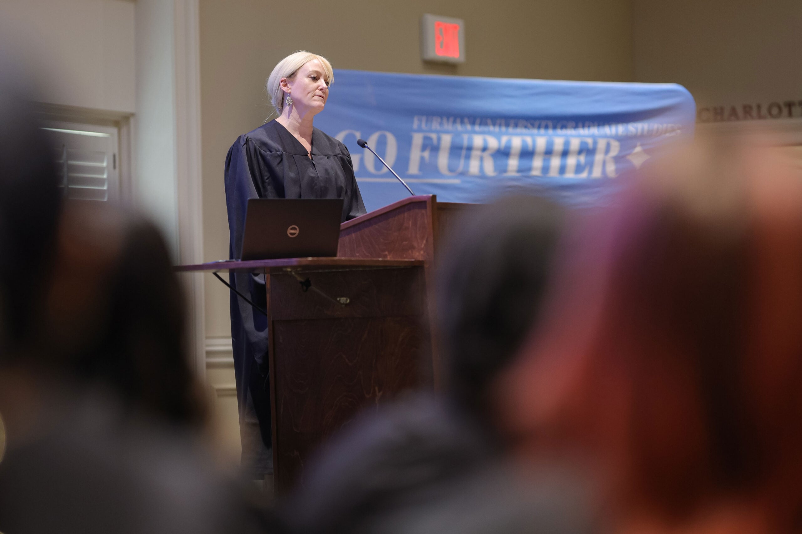 Woman stands at podium in graduation attire