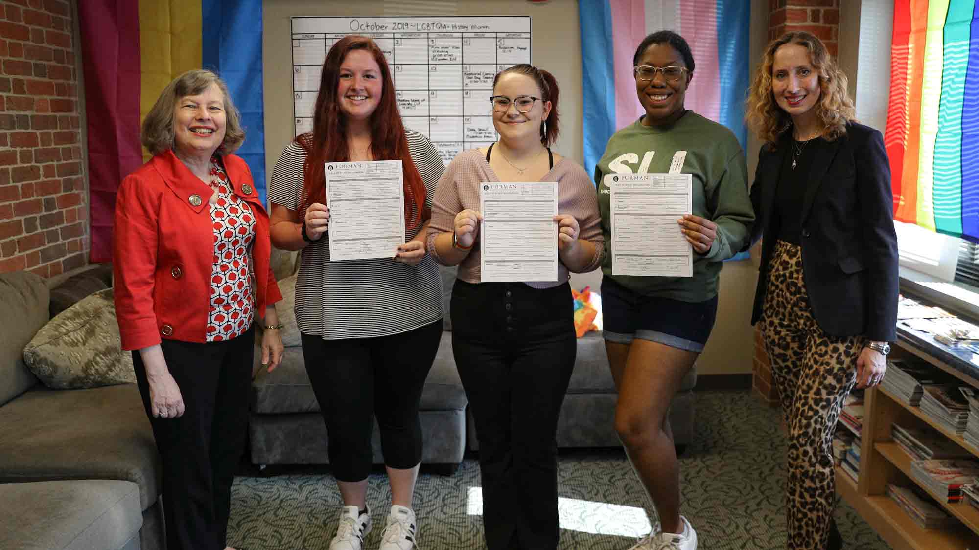 Students and professors holding their new major papers for WGS