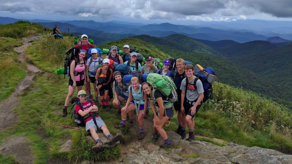 Students standing on the top of a small mountain, backpacking