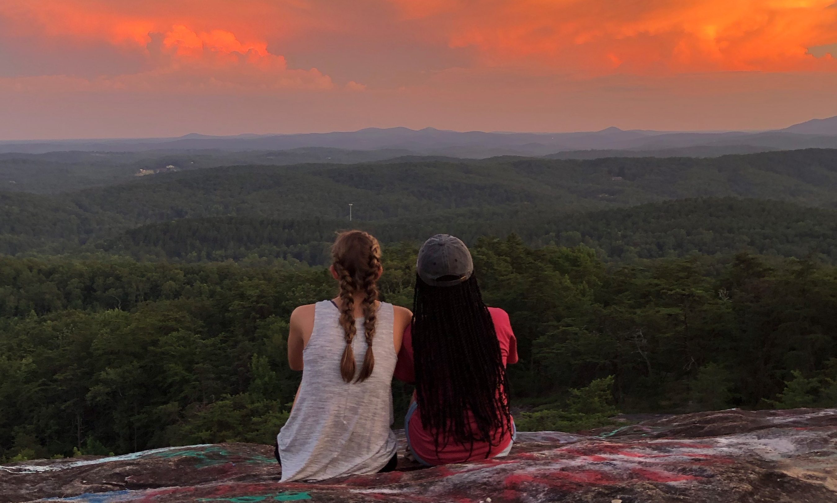 Students sitting on bald rock watching the sunset