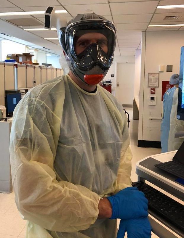 A physician in full personal protective gear: face shield, mask gown and gloves, in a hospital.
