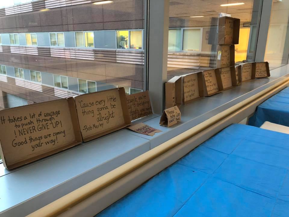 Words of inspiration are written on small cardboard signs lined up along a window sill. 