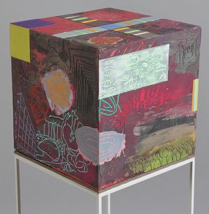 a 12-inch cube on a stand with paintings, etchings and other designs.