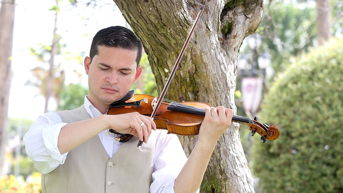 Latino man playing violin outdoors