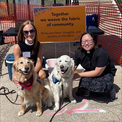Two smiling female ministers pose with very good dogs.