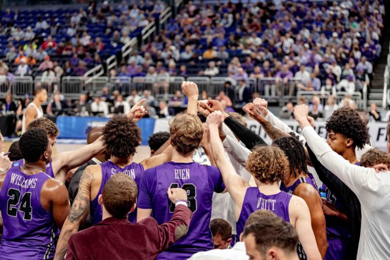 Furman basketball team raises fists in a huddle
