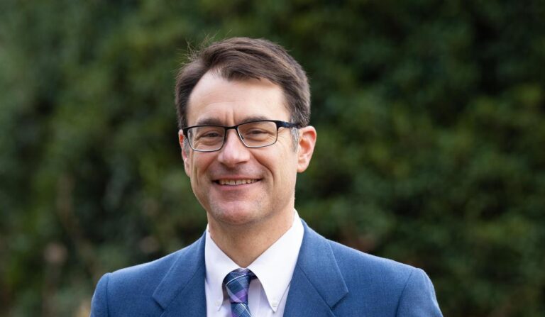 white man in glasses wearing blue suit