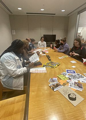 Students study papers around a conference table in a library.