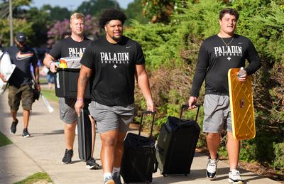 athletes carrying suitcases and dorm supplies