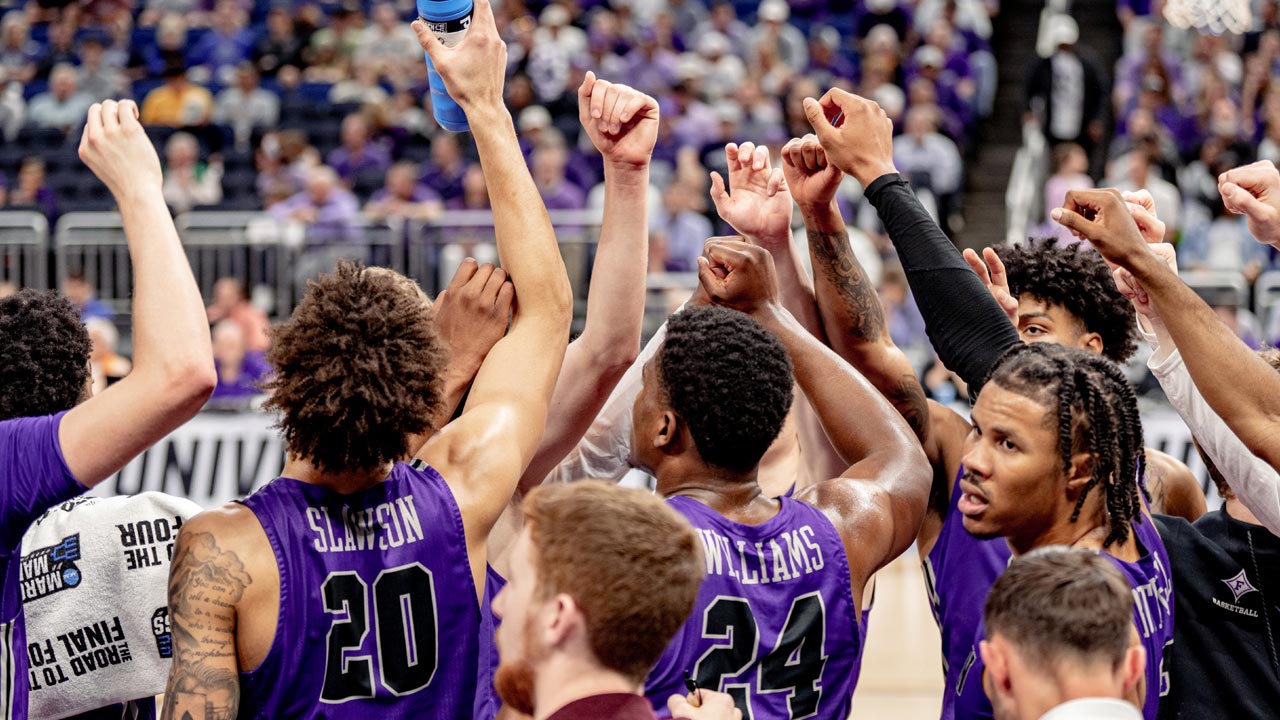 furman basketball team raises fists in a huddle at a game