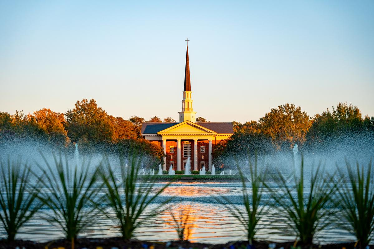 a chapel with steeple, fountains in foreground