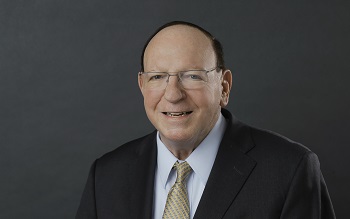 white man wearing glasses and dark suite