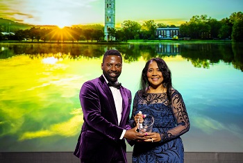 a Black man and a Black woman holding crystal award on stage