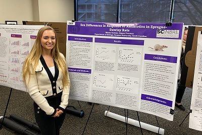 white woman with blond hair stands at poster