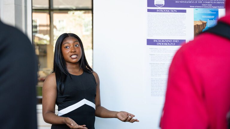 A Black woman in a black dress talks with people about her poster.