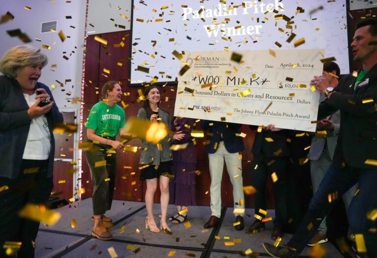 Several people celebrate with a big check and gold confetti.