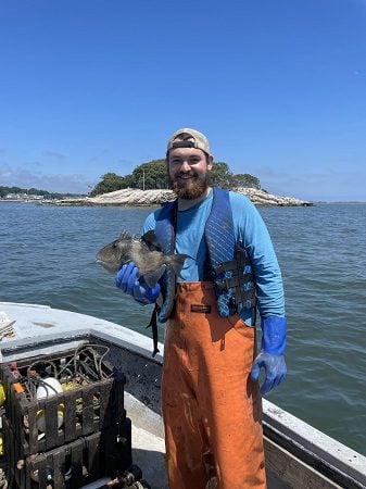 white bearded man in boat holding a fish