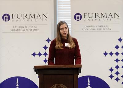 white woman in maroon sweater at podium.