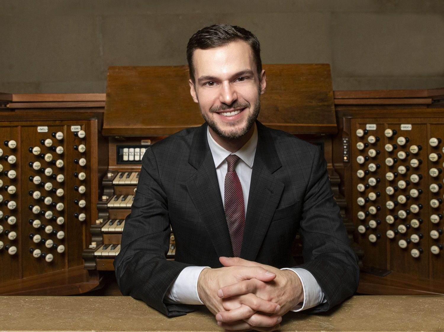 White man sits in front of organ manual