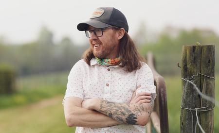 white man in ball cap wears glasses and poses outdoors