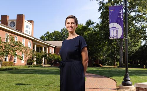 white woman in dark dress, buildings in background