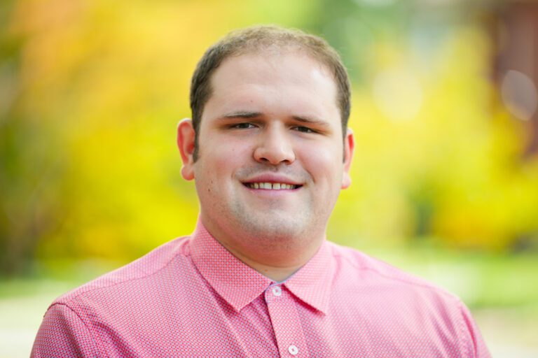 Portrait of Stephen Turner on a path with trees blurred in the background.