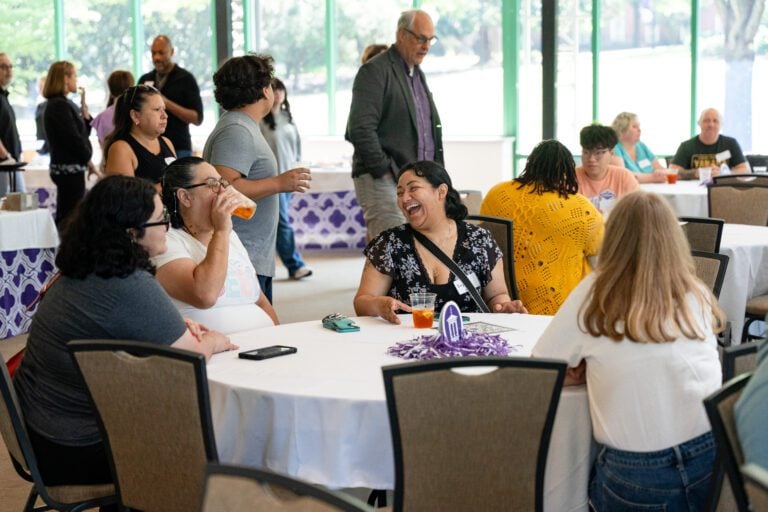 A crowd of students and parents sit at multiple tables during a luncheon.