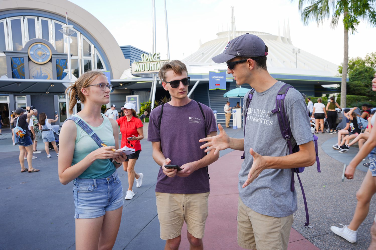 From left, Alyssa Pate ’25, Will Hutson ’26 and Hayes Brown ’26 talk outside of the Space Mountain attraction at Disney World while collecting data. Photo by Nathan Gray, Furman University.