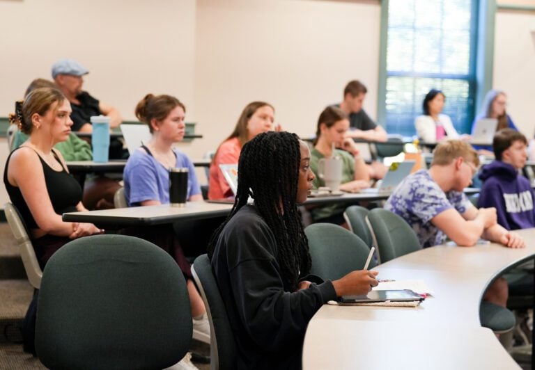 Students sit at tiered tables in a classroom