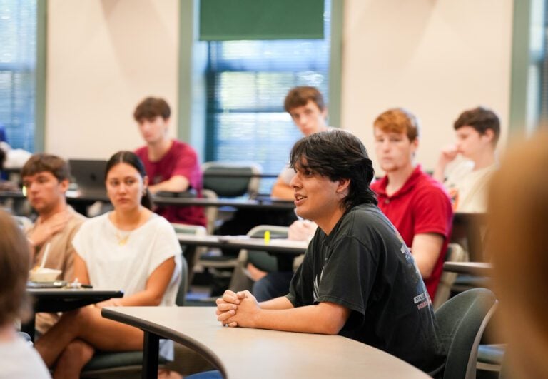 Students sit at tiered tables in a classroom