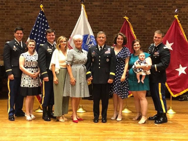 Group photo of a family in Sunday clothes on a stage and smiling.