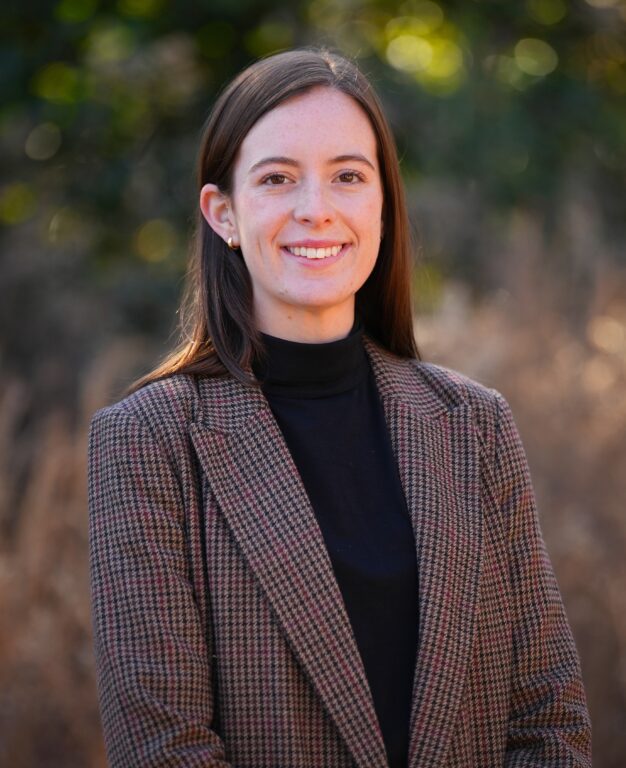 A woman poses for a photo wearing a suit jacket.