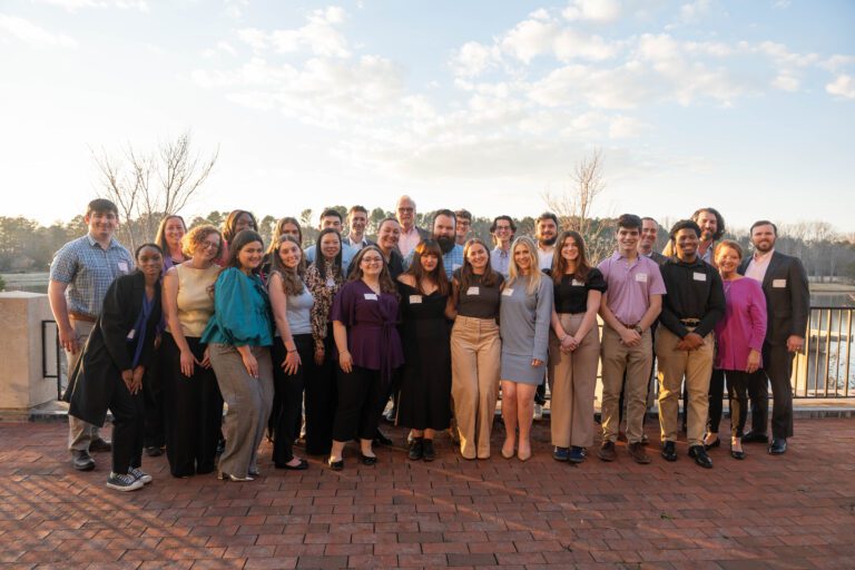A crowd of people gather for a photo outdoors.