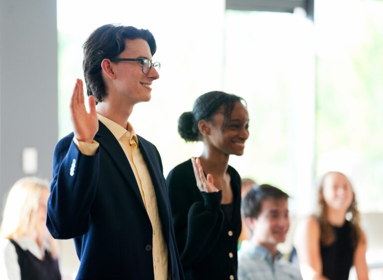 Two young people stand holding up their hands as they are sworn in to a student government association