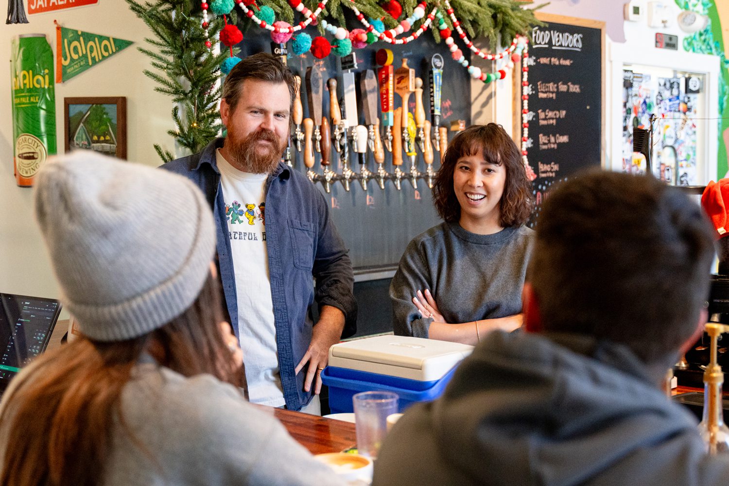 Deb York ’14, right, and George Linn, talk with customers at Grateful Brew in Greenville, SC. Photo by Owen Withycombe.