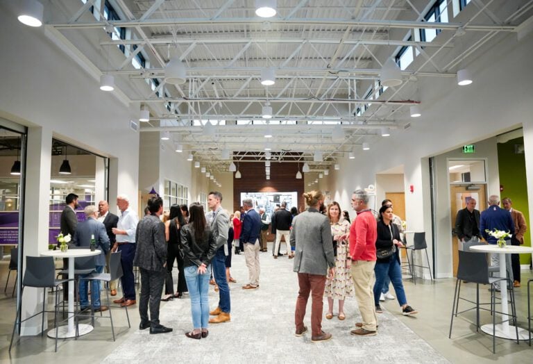 People network inside a bright, large open hall with cocktail tables and chairs.