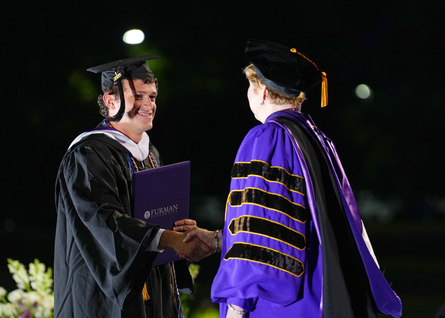 Pete Bard ’25 shakes hands with President Elizabeth Davis after receiving his diploma during the 2025 Commencement Ceremony in Paladin Stadium on May 10.