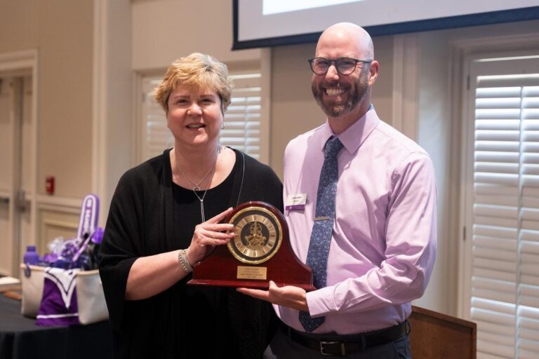 A woman and a man pose with a clock.
