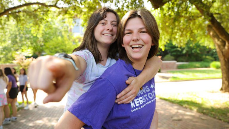 One young woman gives another young woman a piggy back ride.
