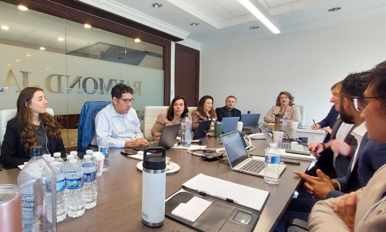 Men and women sit around a long conference room table inside the Atlanta offices of Raymond James, where Furman University staff negotiated a bond deal