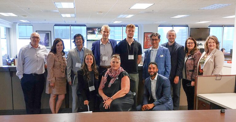 Two rows of people in business attire pose for a photo in an office during a trip of Furman University staff and students to a bond negotiation in Atlanta.