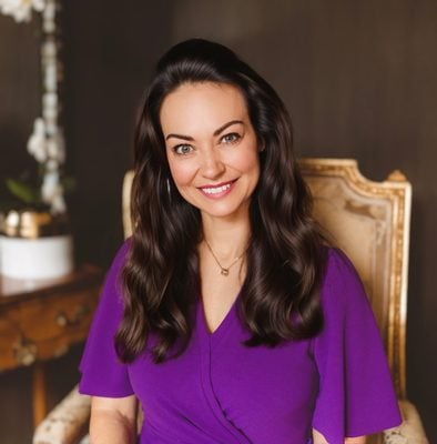 A white woman with long dark hair wears purple and sits in a chair in an indoor photo. Courtney Tollison