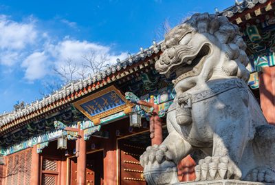 A concrete foo dog guards the entry to an Asian campus building.