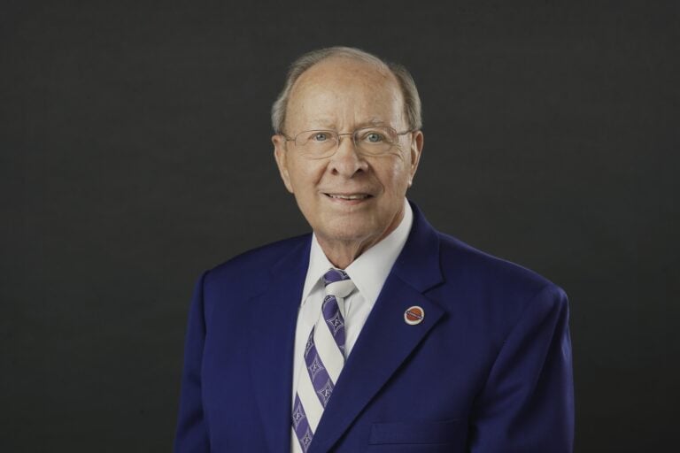 A portrait of an older white man in a blue suit jacket.