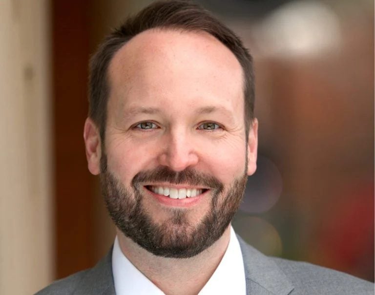 A white man with facial hair wears a sport coat, shirt and tie in an indoor photo. Grant Knox leads The Sarah Reese Lyric Theatre