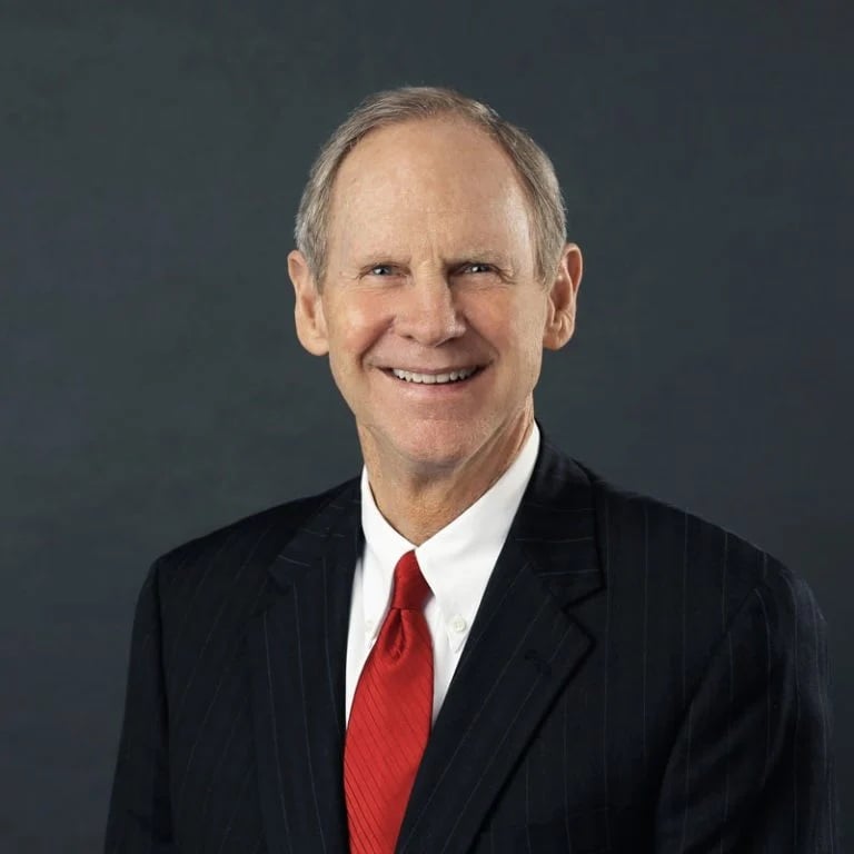 A portrait of an older white man in a suit and red tie