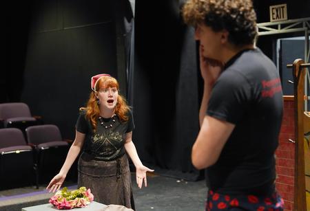 A white woman and a white man rehearse for a play in a black box theater. Theatre/theater